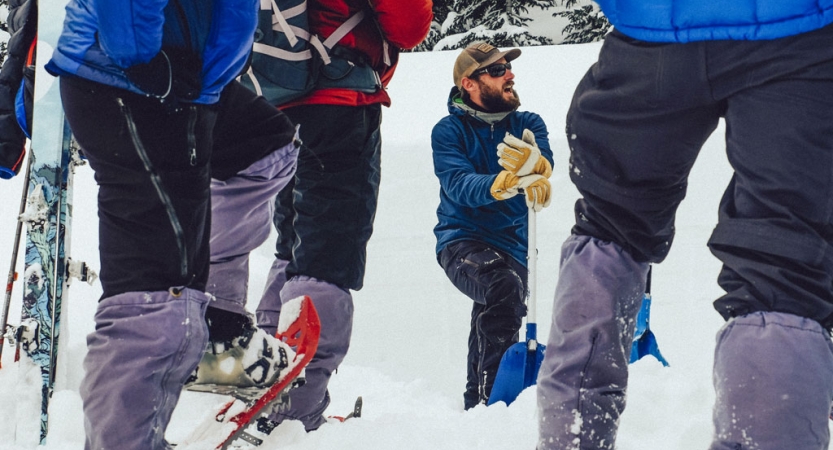 During avalanche training, an instructor appears to be standing in a shallow hole while students look on.